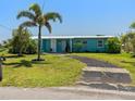 Charming single-story home with a well-manicured lawn, mature palm trees, and a welcoming facade in a quiet neighborhood at 21444 Higgs Dr, Port Charlotte, FL 33952