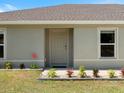 Close-up view of the front door, complemented by decorative plants and a security system sign at 22010 Seyburn Ter, Port Charlotte, FL 33954