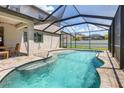 Screened-in pool with tanning ledge, surrounding greenery, and adjacent outdoor dining area at 2427 Carnation Ct, North Port, FL 34289