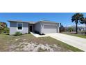 Charming home with a two-car garage and gray exterior paint and a walkway to the front door at 26456 View Dr, Punta Gorda, FL 33983