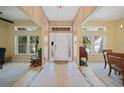 Bright foyer with tiled flooring, high ceilings, decorative windows, and a classic white front door with patterned glass at 2666 Barry Rd, North Port, FL 34286