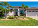 Well-manicured home featuring a three-car garage, tropical landscaping, and a paver driveway at 4174 Perch Cir, Port Charlotte, FL 33948