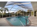 Screened-in pool area with a fountain, stainless ladder and lush surrounding landscaping at 719 Ellicott Nw Cir, Port Charlotte, FL 33952
