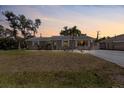 Charming single-story home featuring a well-maintained lawn and a spacious driveway at dusk at 1249 Indus Rd, Venice, FL 34293
