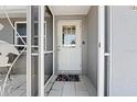 Inviting entryway featuring a tiled floor, a colorful doormat and a white front door with window panes at 1249 Indus, Venice, FL 34293