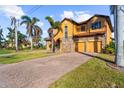 Inviting two-story home with brick driveway, lush lawn, and a three-car garage at 14142 Fort Myers Ave, Port Charlotte, FL 33981