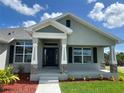 Inviting front porch with decorative columns, a black front door, and professionally landscaped yard at 25156 Rosamond Ct, Punta Gorda, FL 33983