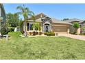 Charming single-story home featuring a stone facade, manicured lawn, and lush landscaping at 27854 Arrowhead Cir, Punta Gorda, FL 33982