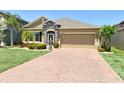Charming single-story home featuring a stone facade, manicured lawn, and a brick driveway at 27854 Arrowhead Cir, Punta Gorda, FL 33982