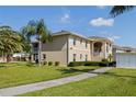 Exterior shot of beige building with lush green grass and palm trees at 5800 Sabal Trace Dr # 1302, North Port, FL 34287