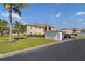 Beige building with palm trees and a carport on a sunny day at 5800 Sabal Trace Dr # 1302, North Port, FL 34287