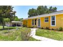 Charming single-Gathering home with a vibrant yellow exterior and well-maintained front yard at 582 Ridgewood Nw St, Port Charlotte, FL 33952