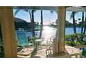 Relaxing lanai with chairs, side table, and serene canal views framed by swaying palm trees at 2575 Brazilia Ct, Punta Gorda, FL 33950