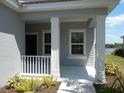 Covered front porch showcasing white columns and railing, complemented by lush landscaping and lake views at 12656 Sagewood Dr, Venice, FL 34293