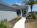 Inviting front porch featuring white columns, a walkway, and a meticulously landscaped yard with a palm tree at 12656 Sagewood Dr, Venice, FL 34293