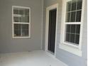 Close-up of the front porch featuring a dark front door, two windows, and neutral siding at 12656 Sagewood Dr, Venice, FL 34293