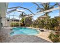 Relaxing screened-in pool area with a stone paver deck and lush landscaping, perfect for outdoor enjoyment at 265 White Marsh Ln, Rotonda West, FL 33947