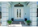 Inviting front entryway with double doors, decorative columns, and a stylish striped doormat at 4569 Kenvil Dr, North Port, FL 34288