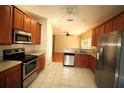 Well-equipped kitchen with stainless steel appliances, white tile floors, and wood cabinetry at 4749 Oakley Rd, North Port, FL 34288
