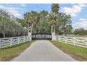 Private driveway with automatic gate entrance, white fencing, and mature palm trees offer a grand welcome at 7200 Riverside Dr, Punta Gorda, FL 33982