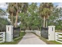 Driveway with iron gates and address markers leads through picturesque white fences and lush greenery at 7200 Riverside Dr, Punta Gorda, FL 33982
