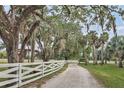 Gravel driveway lined by white crossbuck fencing under a canopy of trees at 7200 Riverside Dr, Punta Gorda, FL 33982