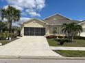 Well-maintained single-story home boasts a two-car garage, lush lawn, and mature palm trees at 7232 W Lenox Cir, Punta Gorda, FL 33950