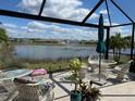 The screened-in patio overlooks a scenic lake view complete with outdoor furniture and a patio umbrella at 7232 W Lenox Cir, Punta Gorda, FL 33950