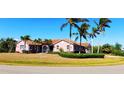 Inviting single-story home boasts a pristine lawn, tropical palm trees, and manicured shrubbery at 8233 Burwell Cir, Port Charlotte, FL 33981