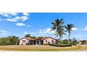 Charming pink single-story home with a well-manicured lawn and several mature palm trees at 8233 Burwell Cir, Port Charlotte, FL 33981