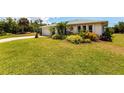 A lush green front lawn leads to this single-story home, showcasing tropical landscaping in the front yard at 11105 Pendleton Ave, Englewood, FL 34224