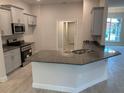 Modern kitchen featuring grey cabinets, granite countertops, stainless steel appliances, and a breakfast bar at 112 Cougar Way, Rotonda West, FL 33947