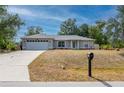 Inviting single-story home with a lush front lawn, a driveway leading to a garage, and a mailbox at 1773 Portage St, North Port, FL 34287