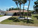 A charming single-story home with a two-car garage, well-kept lawn and mature palm trees at 21035 Exmore Ave, Port Charlotte, FL 33952