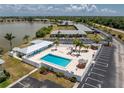 Aerial view of the community pool with lounge chairs, landscaping, and nearby buildings with ample parking at 25225 Rampart Blvd # 1801, Punta Gorda, FL 33983