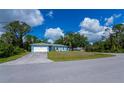 A blue home with a well-manicured lawn, attached garage, and mature trees in a residential neighborhood at 3175 Lakatos St, North Port, FL 34286