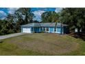 Inviting one-story residence showcasing a blue exterior, lush front yard, and convenient attached garage at 3175 Lakatos St, North Port, FL 34286