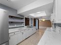 Stylish kitchen equipped with stainless steel refrigerator, open shelving, and a seamless view into the living area at 3561 Middletown St, Port Charlotte, FL 33952