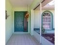 Inviting front porch with tiled floor, teal door and decorative hanging plants at 4461 La France Ave, North Port, FL 34286