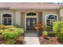 Inviting entryway with double doors, decorative sidelights, and lush landscaping, showcasing curb appeal at 1102 Hunt Club Ln, Valrico, FL 33594