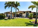 Lovely single-story home featuring a well-maintained lawn, palm trees, and an arched entryway at 25179 Campos Dr, Punta Gorda, FL 33983