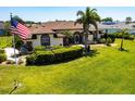 Charming home with manicured lawn, palm trees, and American flag waving in the front yard at 25179 Campos Dr, Punta Gorda, FL 33983