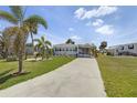 Well-manicured lawn and landscaping with a driveway leading to a single story home with car port at 3305 Blue Jay Ln, Englewood, FL 34224