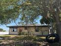 Exterior shot of the back of the home with white siding, windows, and a tire swing in the yard at 3538 Pinetree St, Port Charlotte, FL 33952
