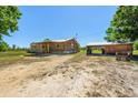 Ranch-style wooden home featuring a covered porch, a detached garage, and surrounded by a spacious, grassy yard at 47350 Bermont Rd, Punta Gorda, FL 33982