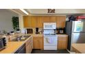 Functional kitchen with wooden cabinets, an oven, microwave, and stainless steel sink, perfect for culinary creations at 2275 S Mccall Rd # 103, Englewood, FL 34224