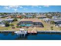 Aerial view of a waterfront home with a screened-in pool, boat dock, and lush landscaping at 283 Fields Se Ter, Port Charlotte, FL 33952