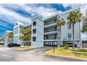 Stylish waterfront condo building with blue exterior, multiple balconies, mature palm trees, and covered parking at 1750 Jamaica Way # 312, Punta Gorda, FL 33950