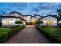 Stunning estate featuring a long brick driveway and meticulously manicured landscaping at dusk at 2107 4Th Street W Ct, Palmetto, FL 34221