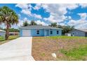 Charming single-story blue home featuring an attached garage and a well-manicured lawn at 21480 Eldred Ave, Port Charlotte, FL 33952
